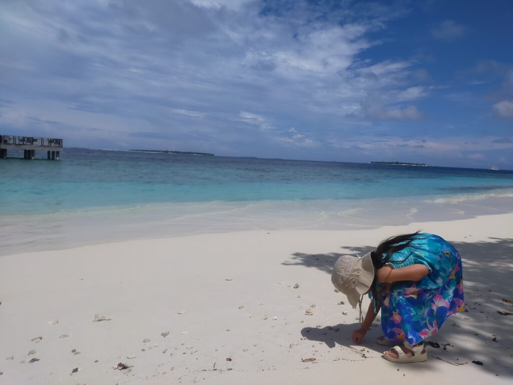 モルディブの白い砂浜で貝殻拾いをする娘
