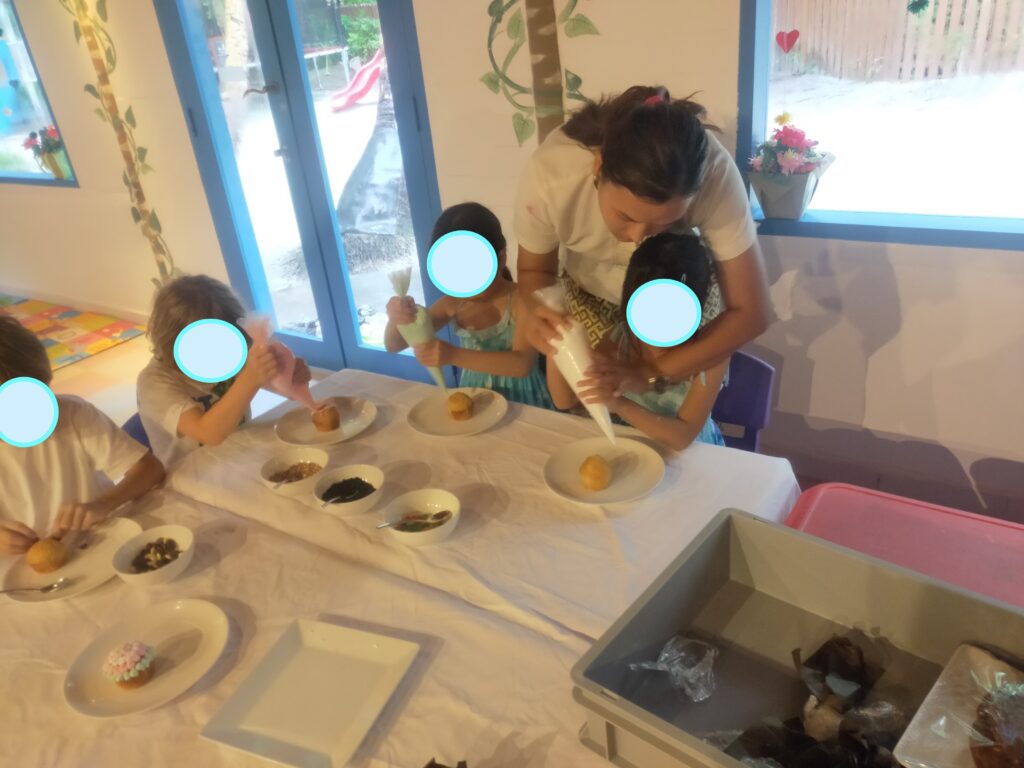 キッズクラブでスタッフと一緒にカップケーキ作りをする子供たち